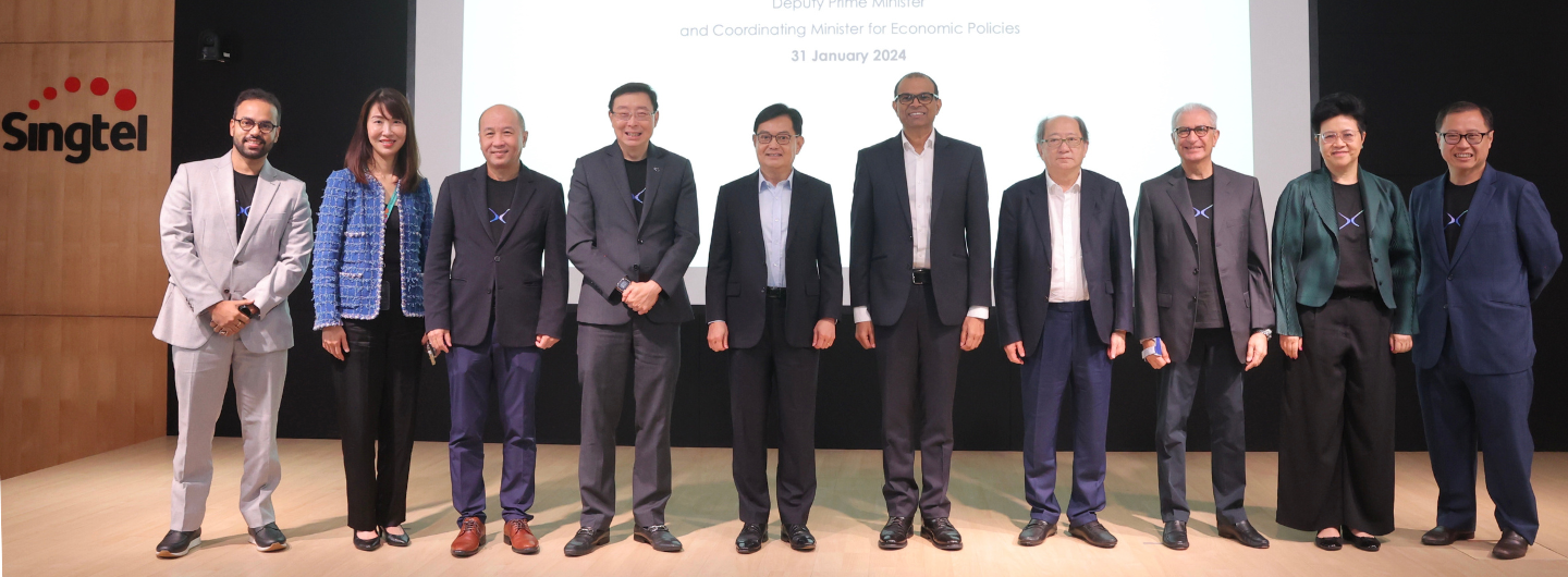 Ten people in business attire stand in a row. Singtel logo visible on wood paneling.